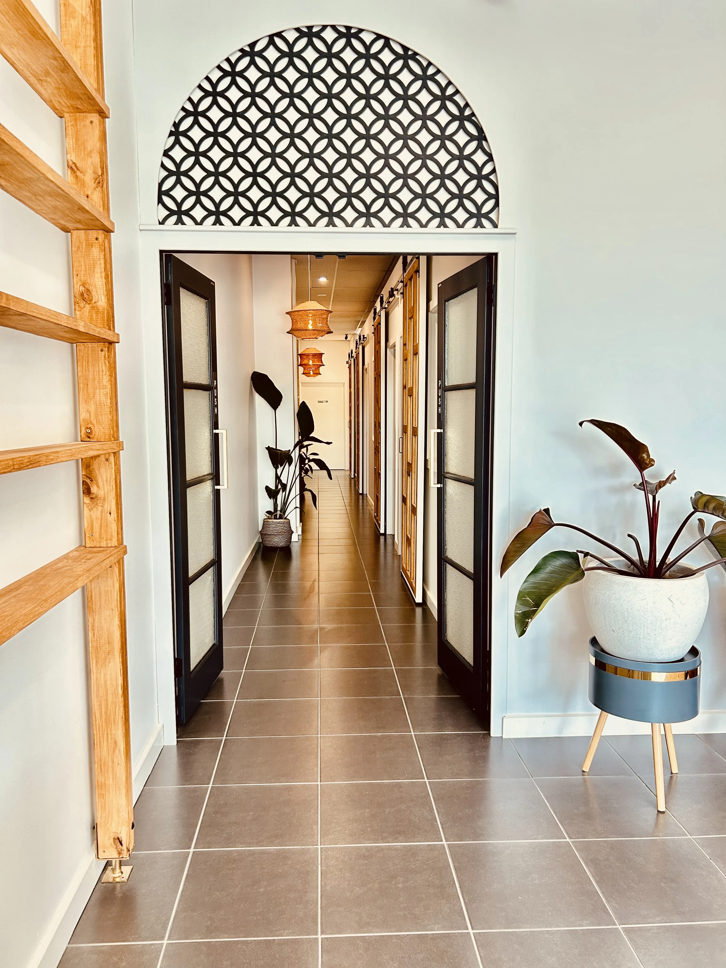 The treatment-room corridor at Siam Ivory Kew — arched Thai lattice, rattan lanterns receding down the hall
